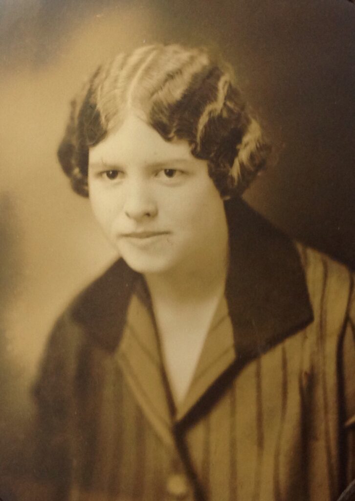 Sepia-toned studio portrait of a young woman with short wavy hair wearing a striped blazer.